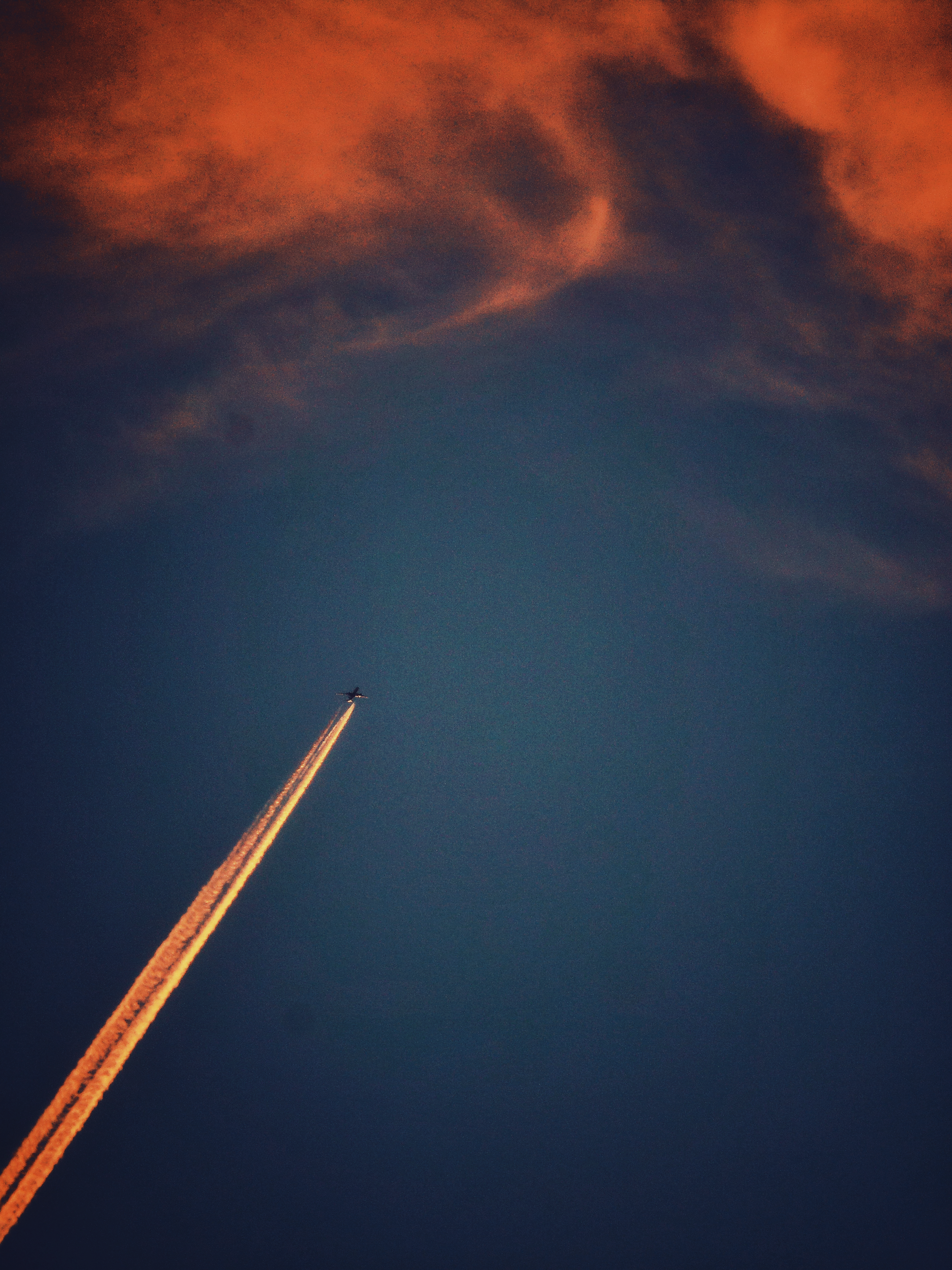 A plane (with trails) heading towards clouds